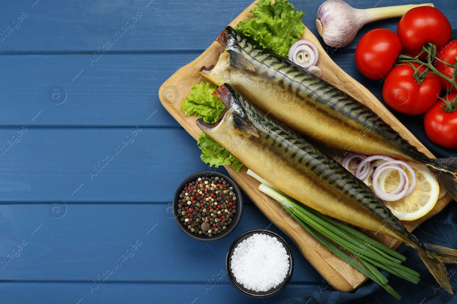 Photo of Delicious smoked mackerels and products on blue wooden table, flat lay. Space for text