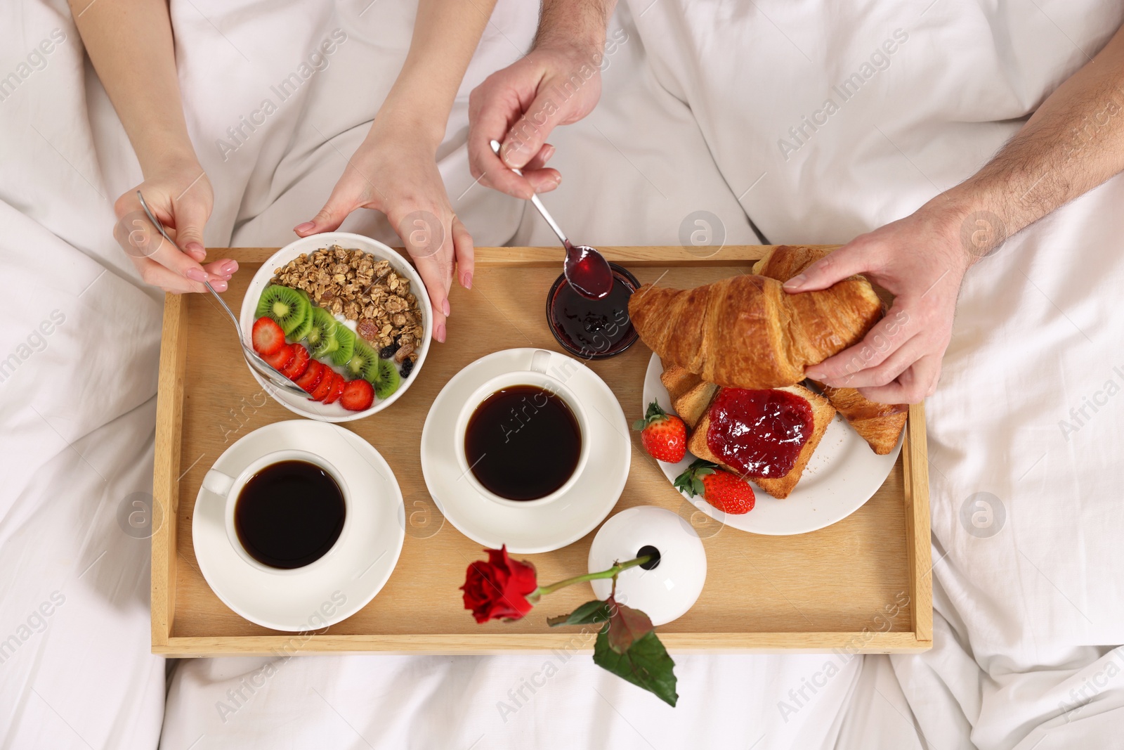 Photo of Couple eating tasty breakfast in bed, top view