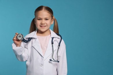 Photo of Little girl in medical uniform with stethoscope on light blue background. Space for text