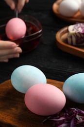 Photo of Naturally painted Easter eggs on black wooden table, closeup. Red cabbage used for coloring