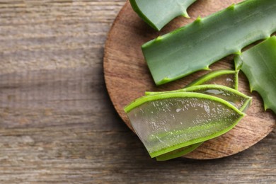 Slices of fresh aloe vera leaves with gel on wooden table, top view. Space for text
