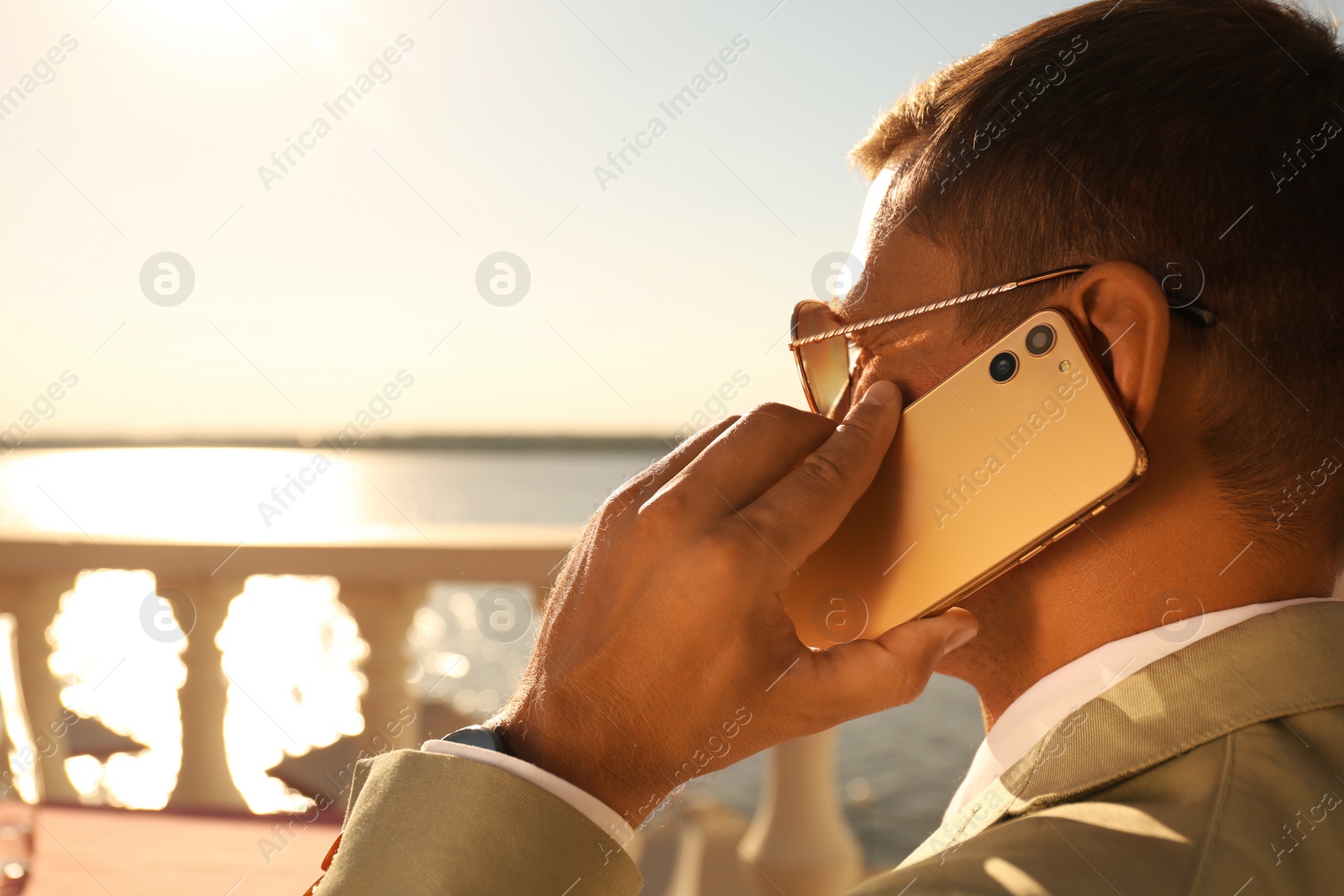 Photo of Businessman talking on smartphone in outdoor cafe