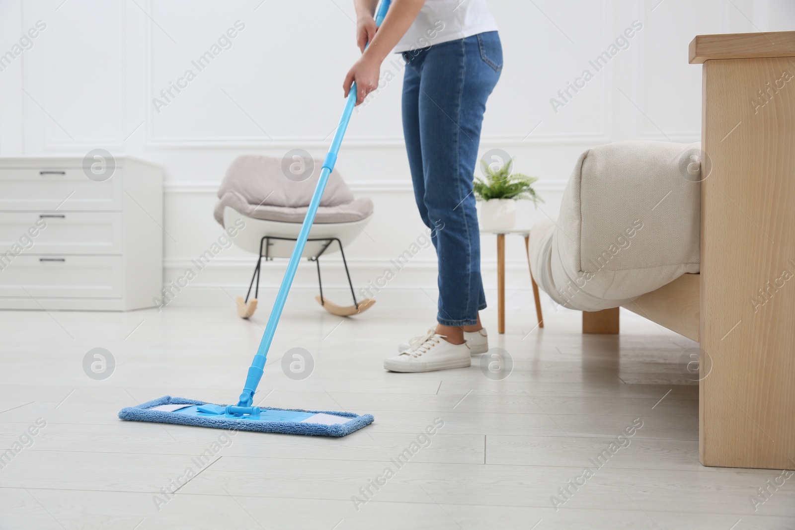 Photo of Woman cleaning parquet floor with mop at home, closeup