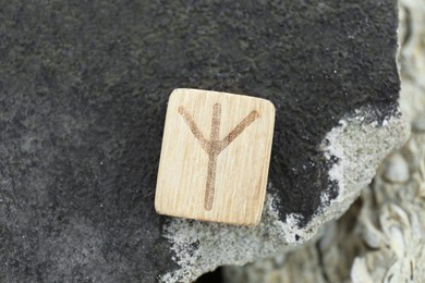 Wooden rune Algiz on stone outdoors, closeup