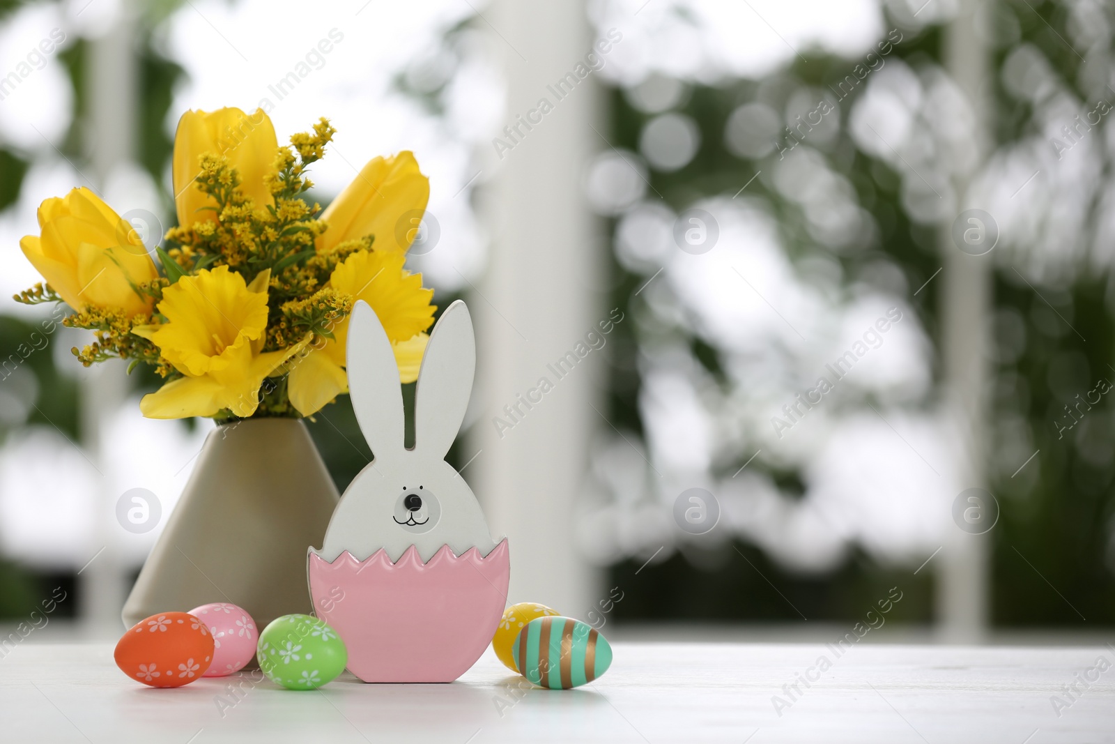 Photo of Festive composition with Easter eggs on table against blurred window, space for text