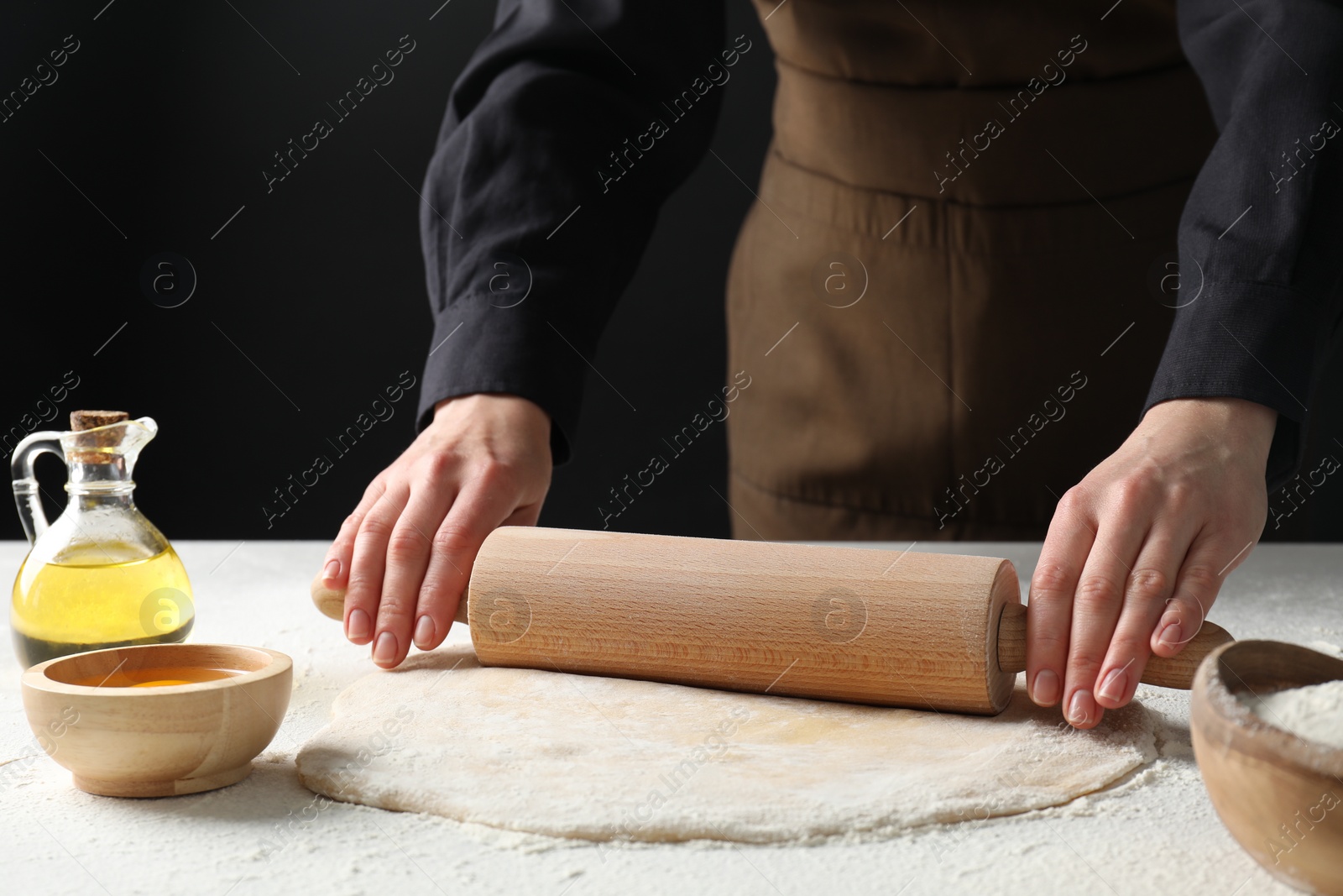 Photo of Woman rolling raw dough at table, closeup