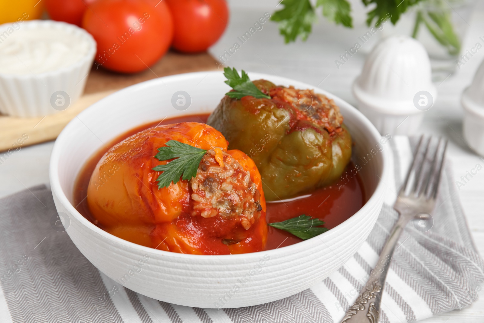 Photo of Delicious stuffed peppers with parsley in bowl on table