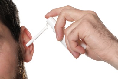 Photo of Man using ear spray isolated on white, closeup