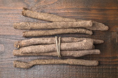 Raw salsify roots on wooden table, flat lay