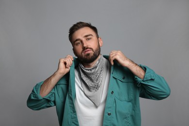Photo of Fashionable young man in stylish outfit with bandana on grey background