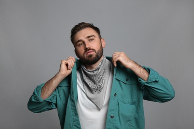 Fashionable young man in stylish outfit with bandana on grey background