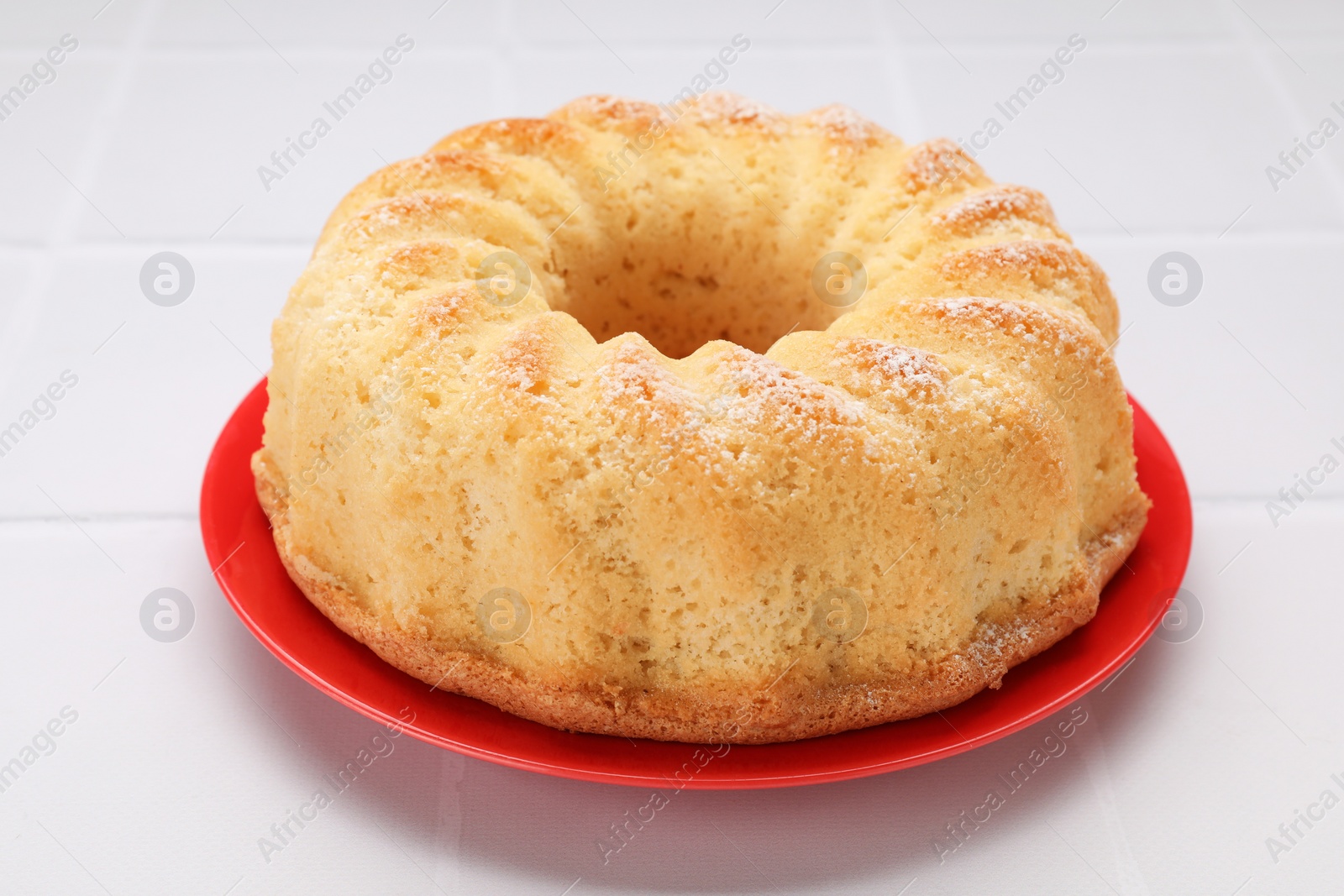 Photo of Delicious freshly baked sponge cake on white tiled table, closeup