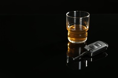 Photo of Car key near glass of alcohol on black table, space for text. Dangerous drinking and driving