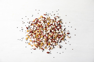 Mixed vegetable seeds on white wooden background, flat lay