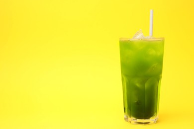 Glass of delicious iced green matcha tea on yellow background, space for text