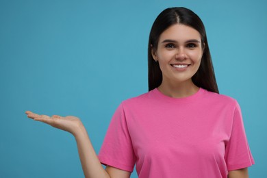 Special promotion. Happy woman holding something on light blue background