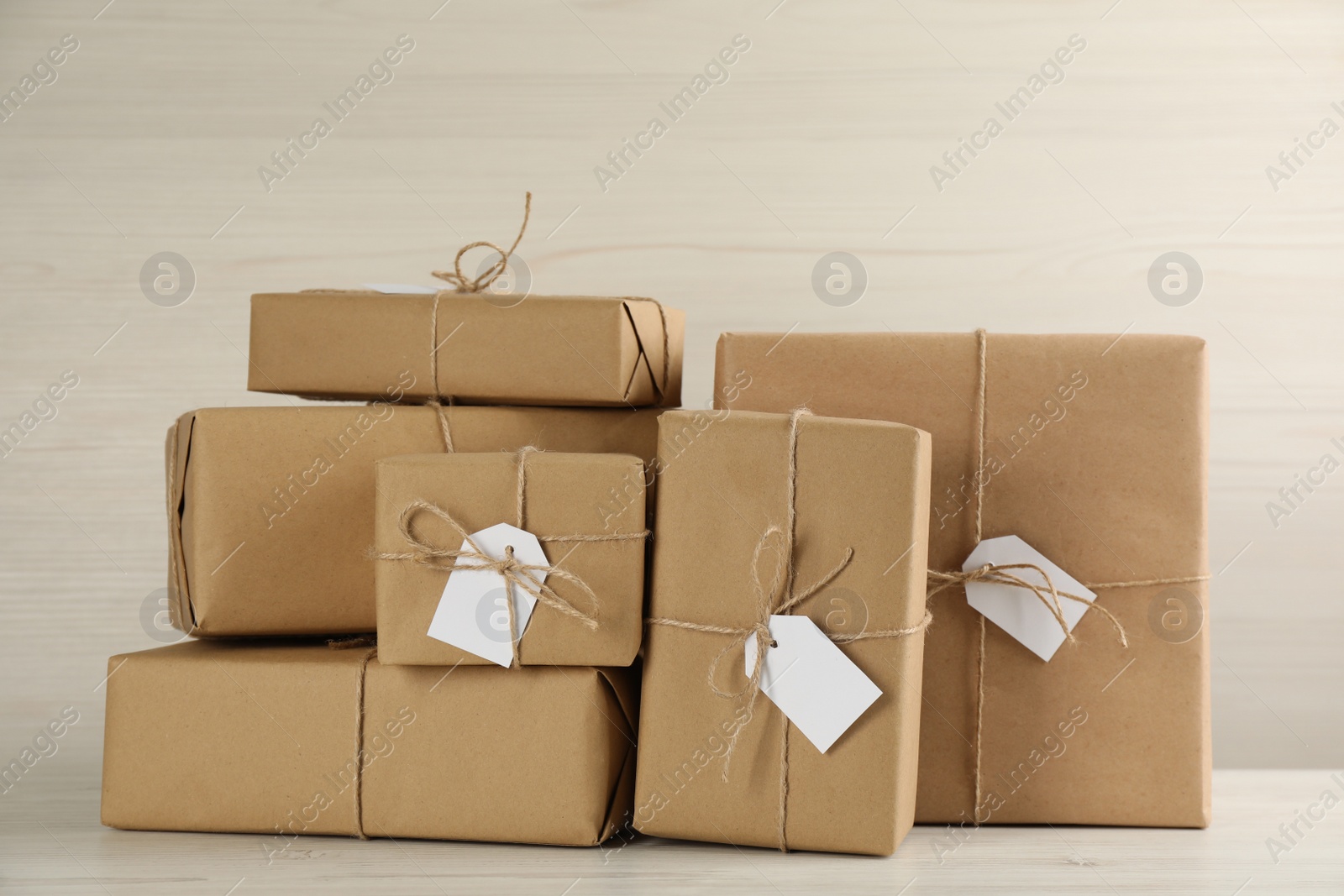 Photo of Parcels wrapped in kraft paper with tags on white wooden table