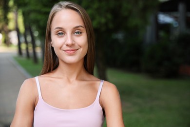 Portrait of beautiful young woman in park, space for text