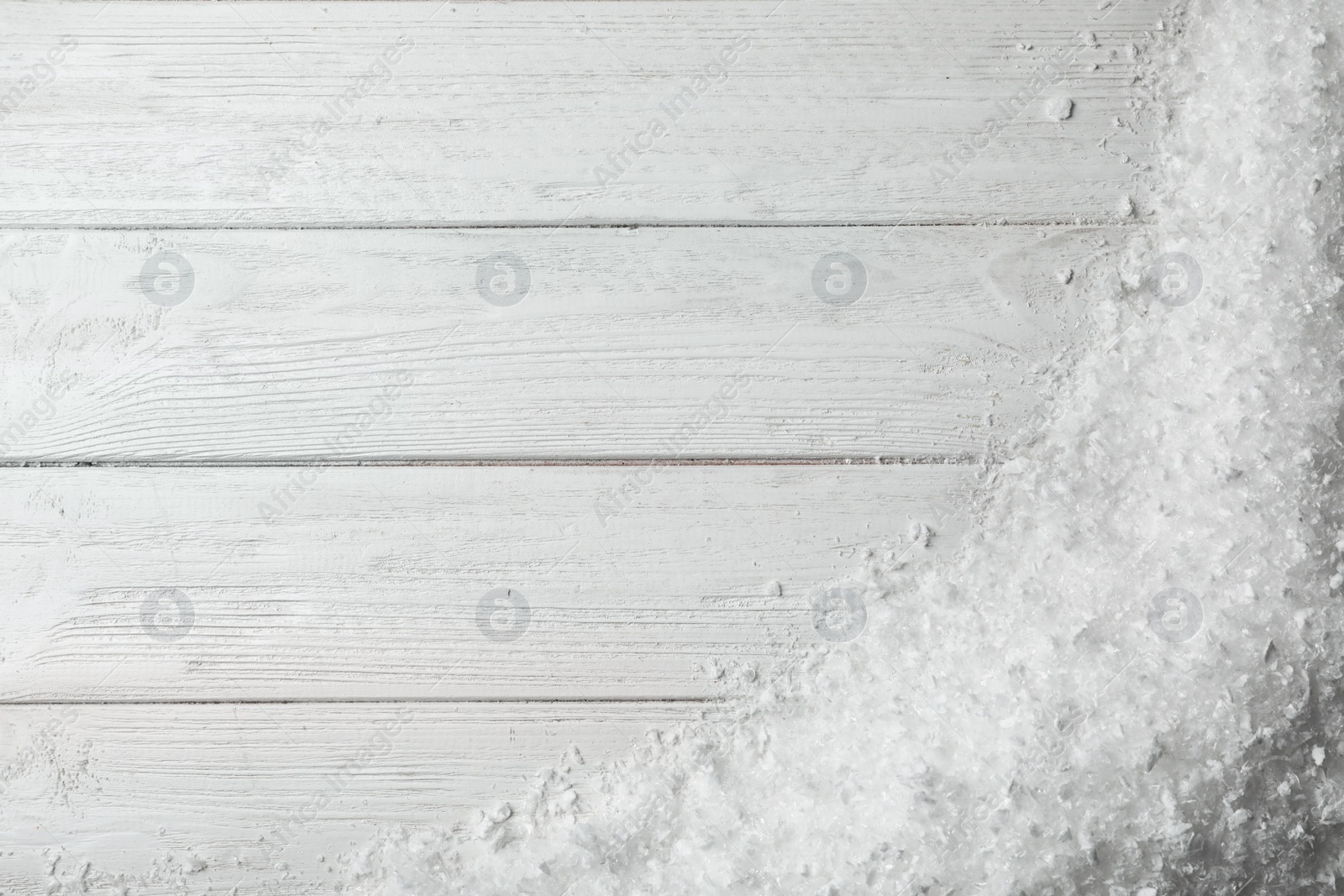 Photo of White snow and space for text on wooden background, top view