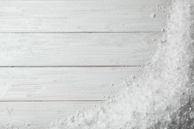 White snow and space for text on wooden background, top view