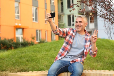 Photo of Handsome mature man taking selfie in park. Space for text