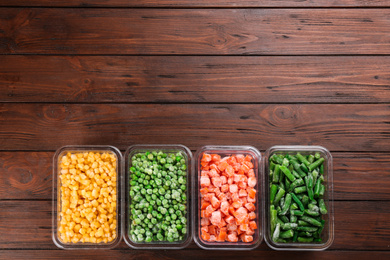 Photo of Different frozen vegetables on wooden table, flat lay. Space for text