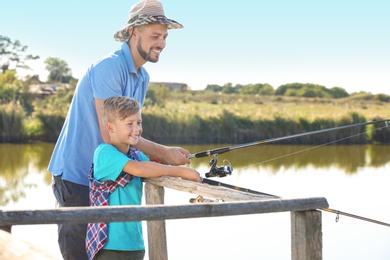 Photo of Father and son fishing together on sunny day