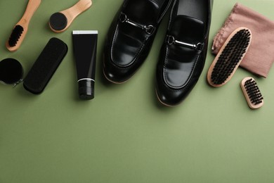 Flat lay composition with shoe care accessories and footwear on green background. Space for text