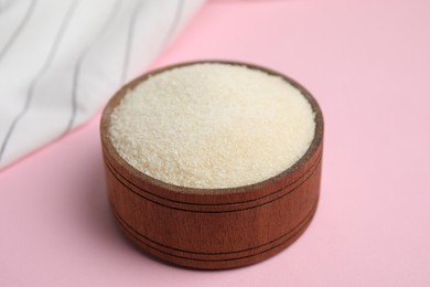 Photo of Gelatin powder in wooden bowl on pink background, closeup