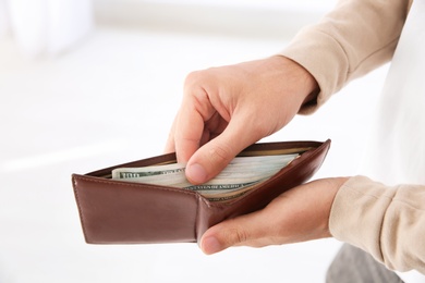 Photo of Man holding wallet with money indoors, closeup