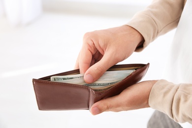 Man holding wallet with money indoors, closeup