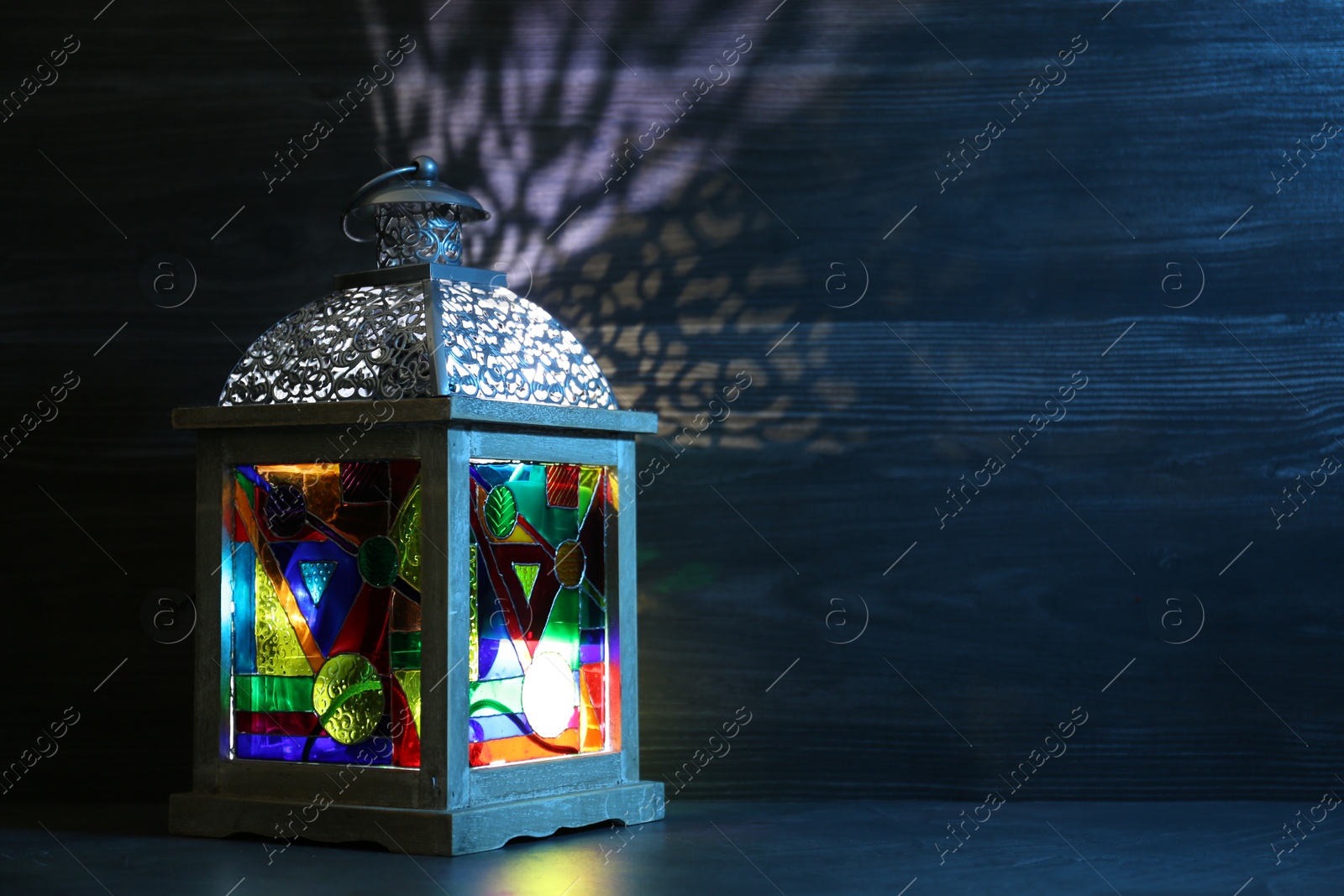 Photo of Decorative Arabic lantern on table against dark background. Space for text