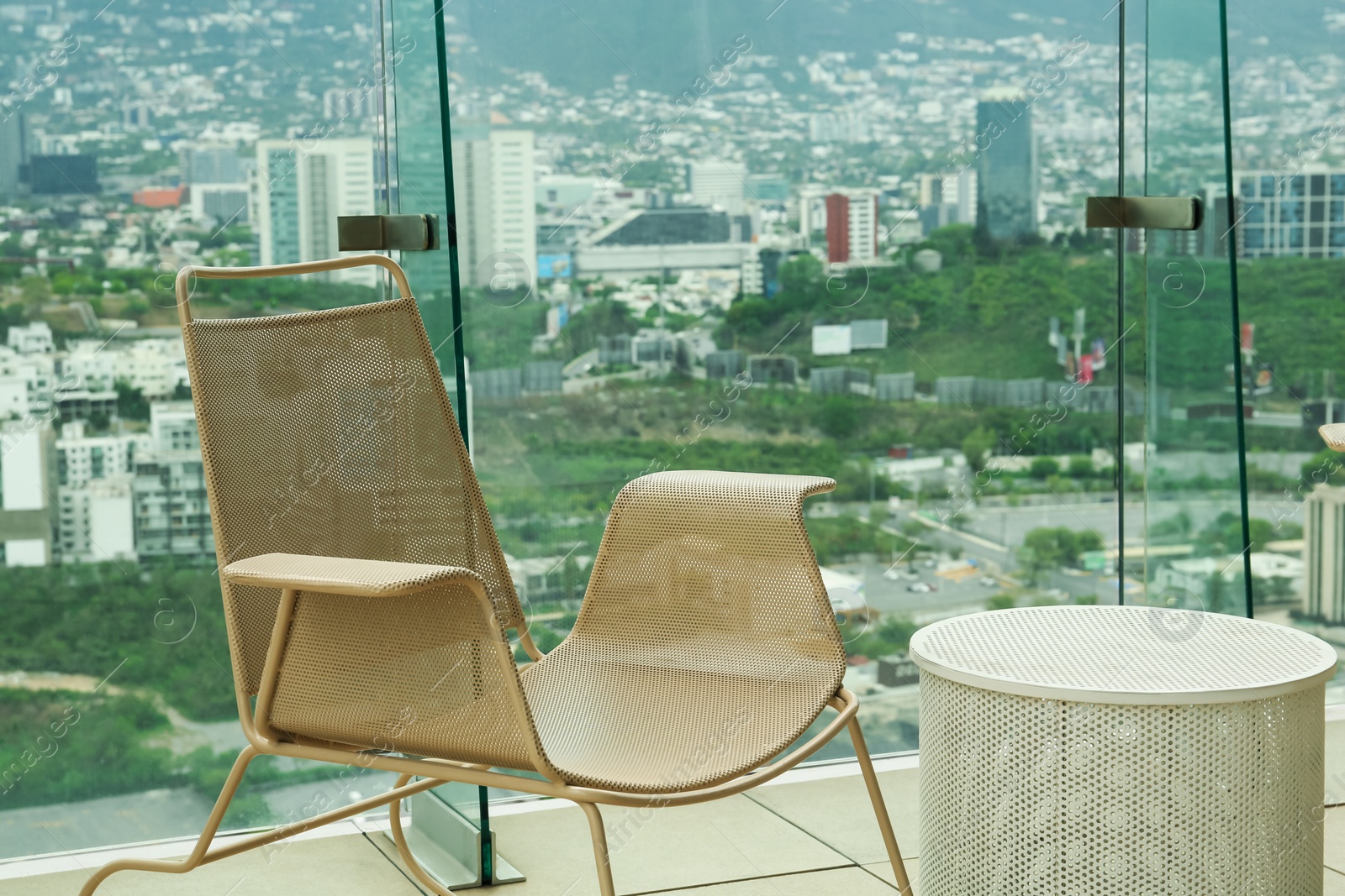 Photo of Coffee table and chair against picturesque landscape of city in cafe