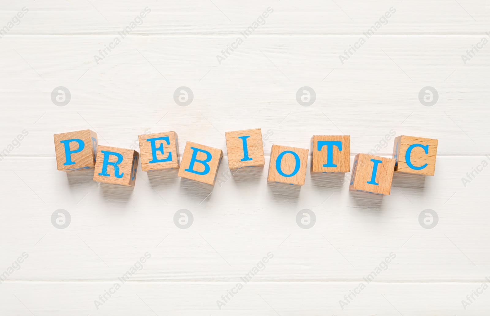 Photo of Word Prebiotic made of cubes with letters on white wooden table, top view