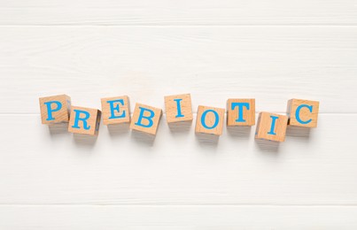 Photo of Word Prebiotic made of cubes with letters on white wooden table, top view