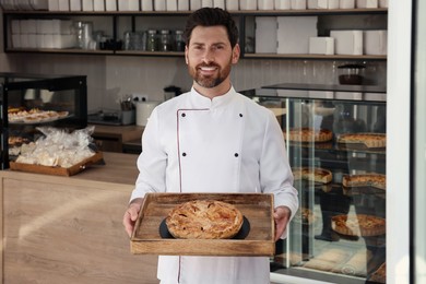 Professional baker with freshly baked pastry in store