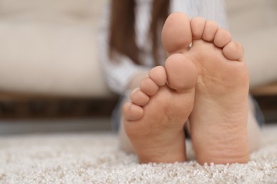 Photo of Woman sitting on soft brown carpet at home, closeup. Space for text