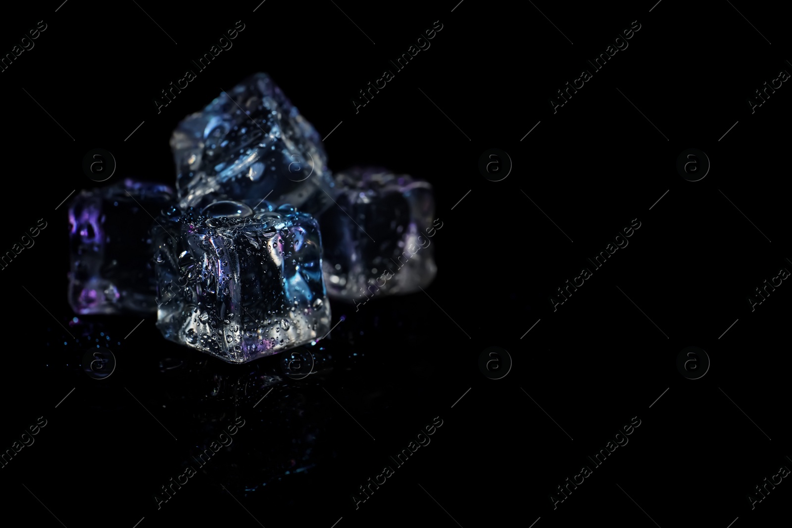 Photo of Pile of crystal clear ice cubes on black background. Space for text