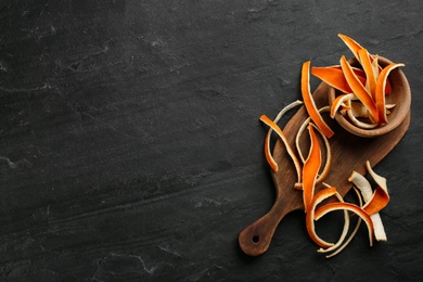 Dry orange peels on black table, flat lay. Space for text