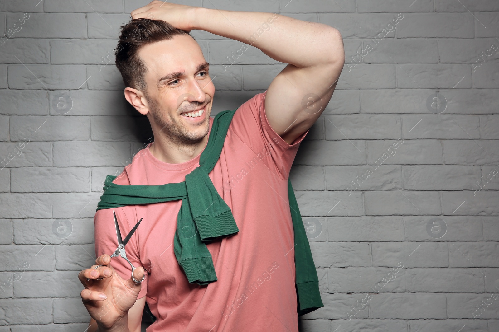 Photo of Professional hairdresser with scissors on brick wall background