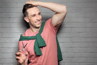 Photo of Professional hairdresser with scissors on brick wall background