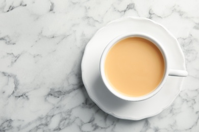 Photo of Cup with black tea and milk on marble table, top view