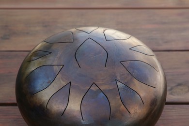Photo of Steel tongue drum on wooden table, closeup. Percussion musical instrument