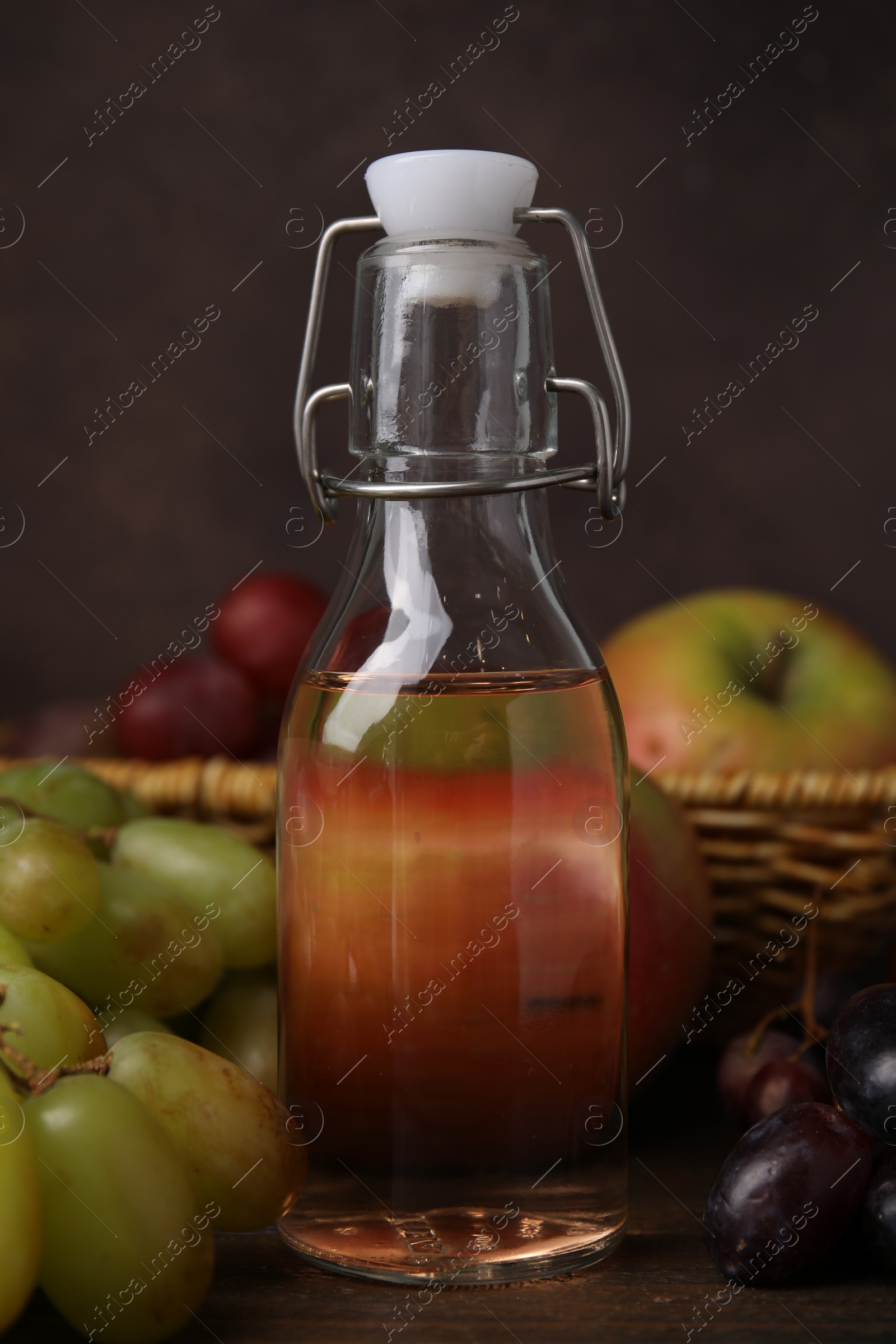 Photo of Vinegar in glass bottle and grapes on wooden table