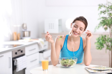 Young woman in fitness clothes having healthy breakfast at home. Space for text