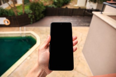 Woman holding smartphone with blank screen outdoors, closeup