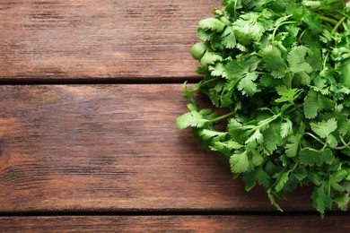 Photo of Fresh coriander on wooden table, top view. Space for text