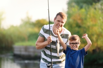 Photo of Dad and son fishing together on sunny day