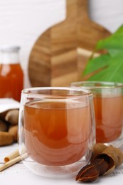 Photo of Tamarind juice and fresh fruits on white table, closeup