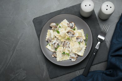 Delicious ravioli with tasty sauce and mushrooms served on black table, flat lay. Space for text